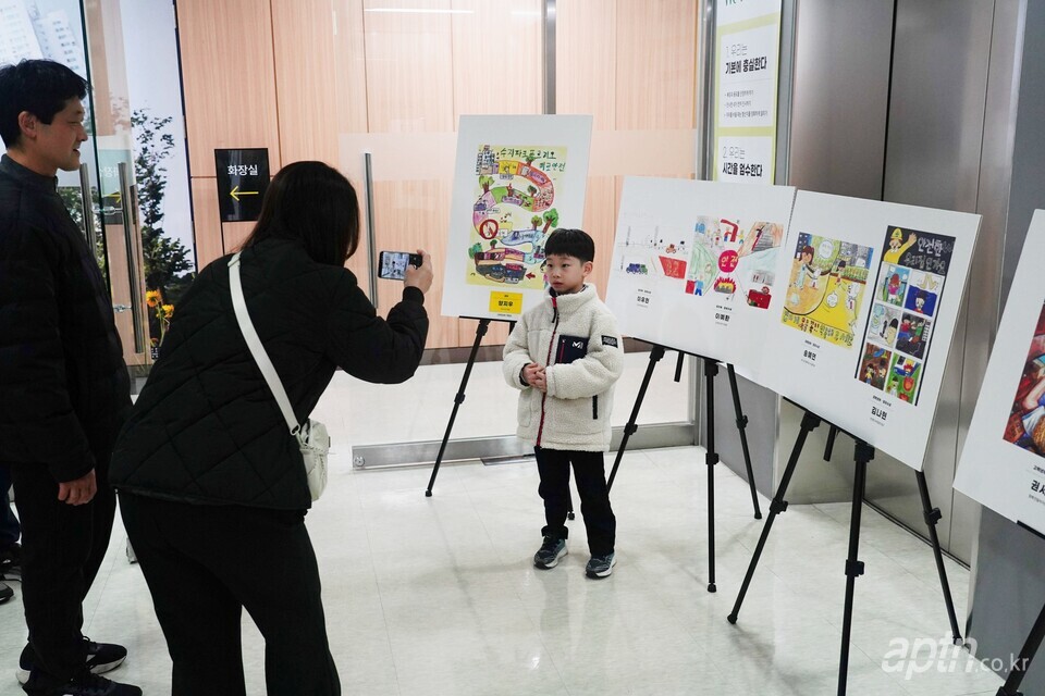 전시된 작품 앞에서 사진을 찍고 있는 어린이. [사진=우리관리]